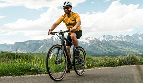 A man rides his Fiido C21 ebike amidst mountain scenery.