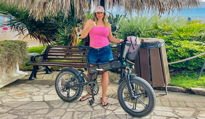 Eleonora stands next to a Fiido M1 Pro electric bike with a bench and greenery in the background.