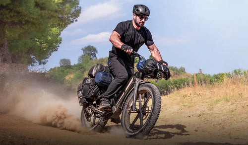 A man speeds through the mountains on a Fiido Titan fat-tire bicycle.