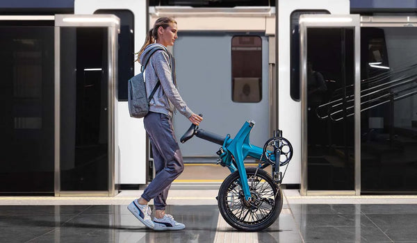 A woman walking pushing a folding e-bike