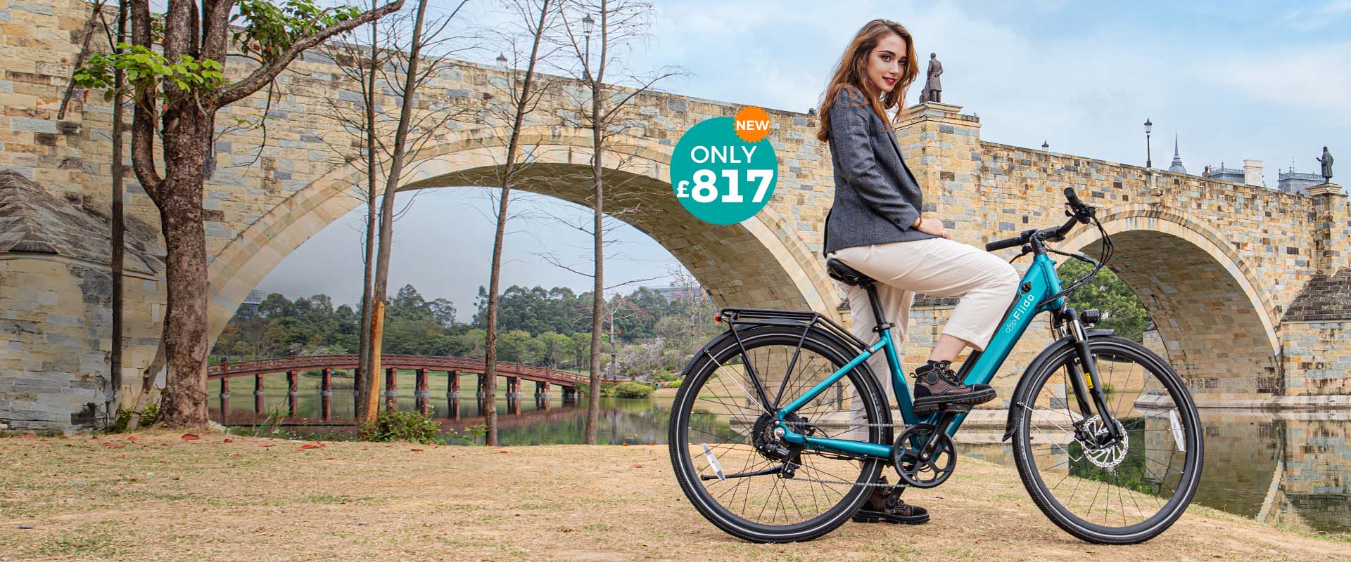 A woman rides a Fiido C11 electric bike by the river under a bridge.