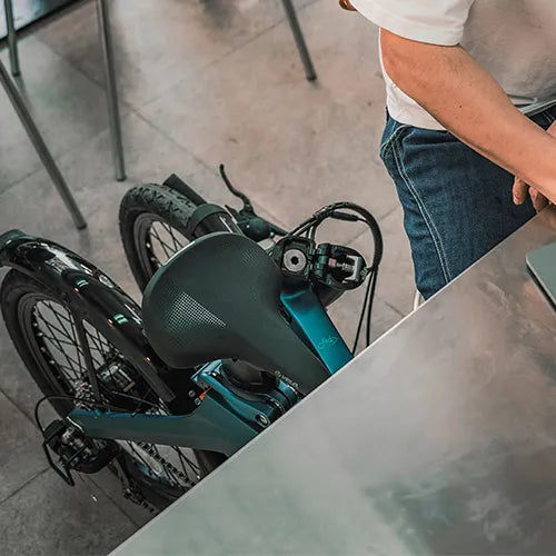 Man folding a Fiido folding e-bike under desk